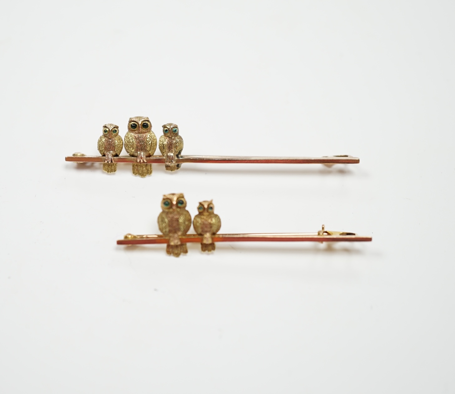 Two early 20th century 9ct owl bar brooches, with cabochon set eyes, largest 63mm, gross weight 6.9 grams.